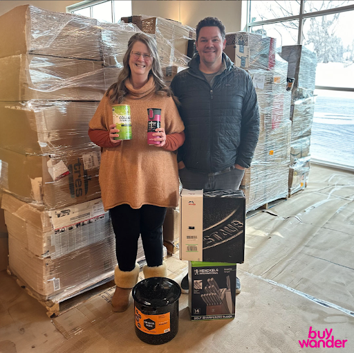 Two BuyWander customers posing with pallet and product pickups inside the warehouse.