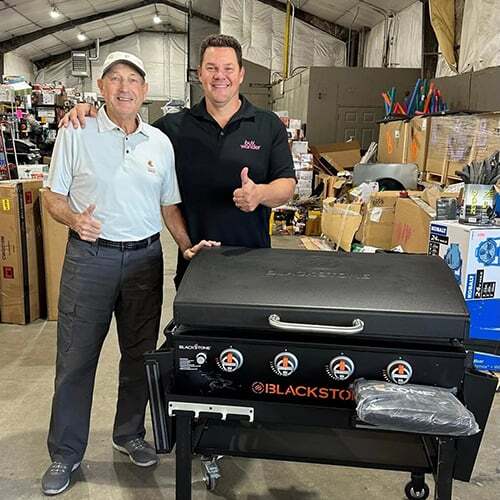 Two BuyWander customers posing with a large grill pickup.